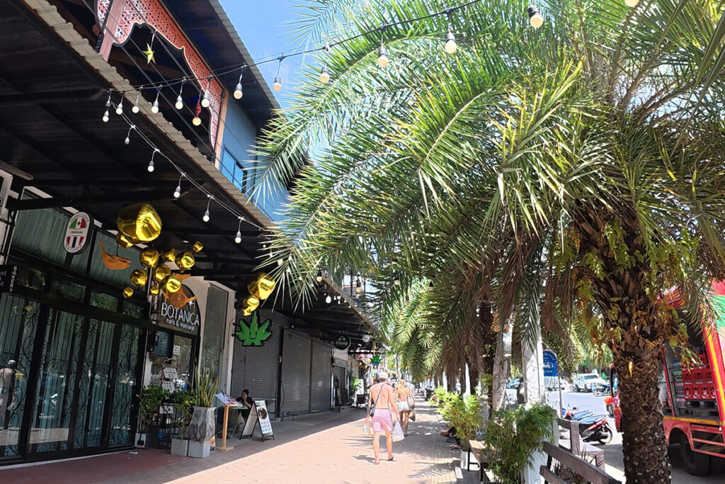 Covered shopping street lined with palm trees, boutiques, and cafes along the Ao Nang strip