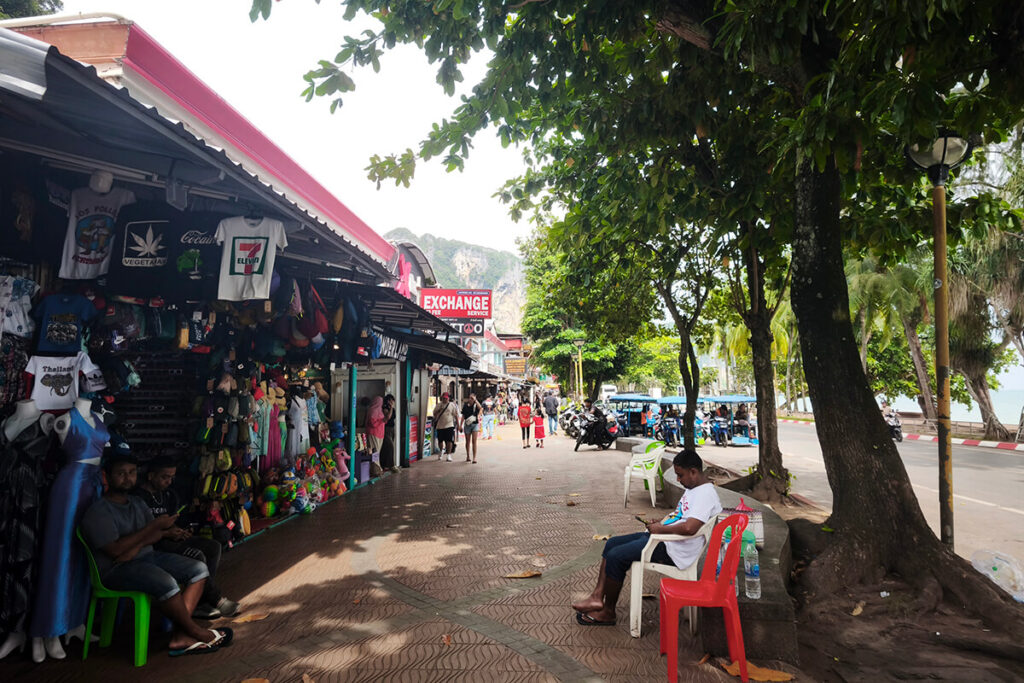 Colourful souvenir stalls and beachwear displays along the shaded pedestrian walkway in Ao Nang