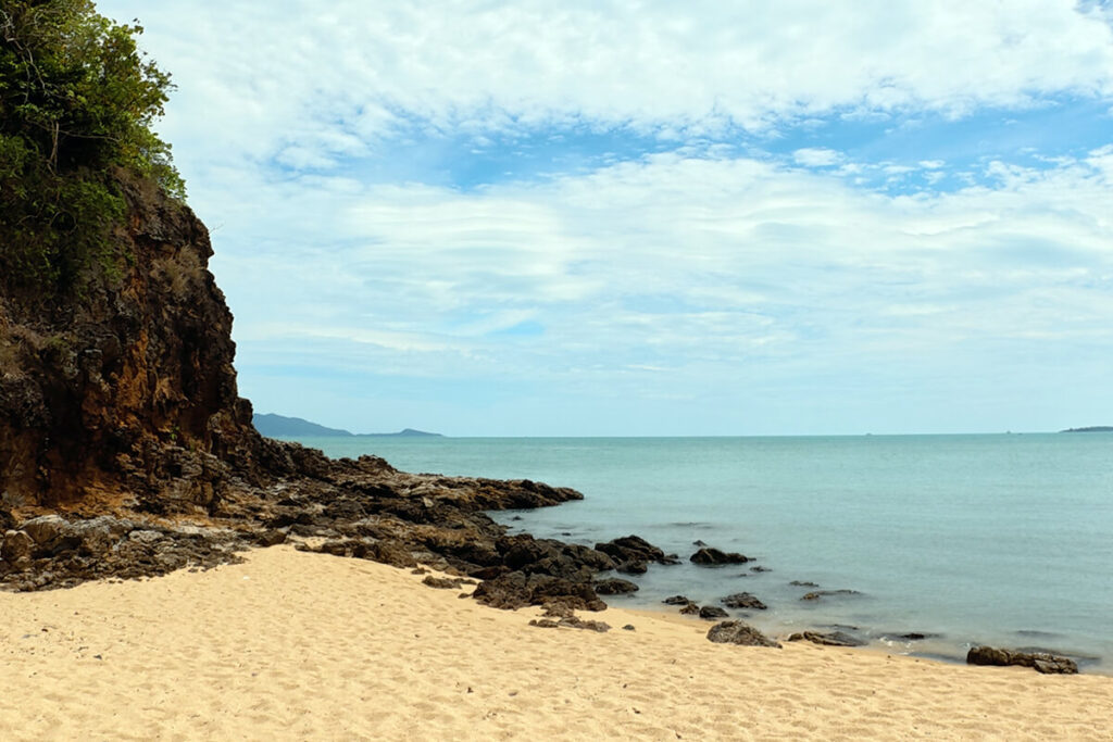 Rocky cliff headland meeting the turquoise sea at the edge of Maenam Beach, Koh Samui
